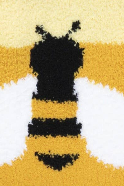 Close-up of a bee-themed sock with black stripes on a yellow and white background