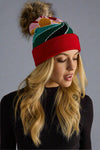 Woman wearing a colorful beanie with a pom-pom on a gray background