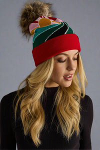 Woman wearing a colorful beanie with a pom-pom on a gray background