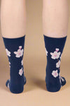 Navy socks with pink floral patterns worn by a person on a light gray background