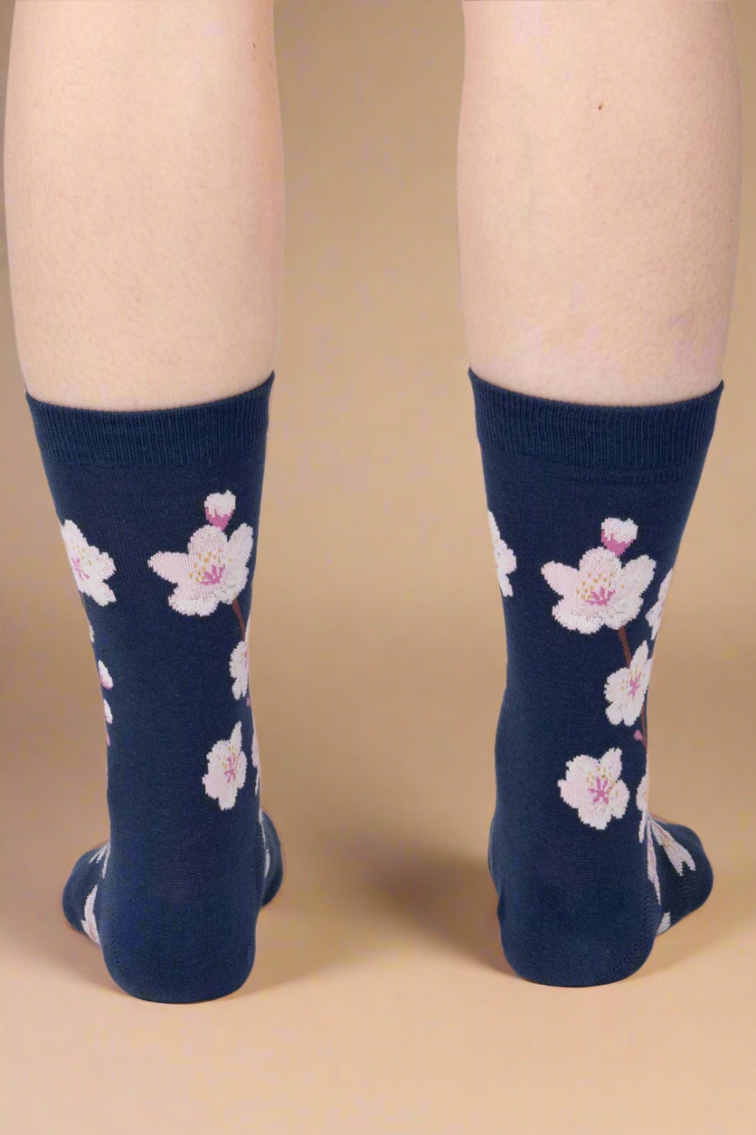 Navy socks with pink floral patterns worn by a person on a light gray background