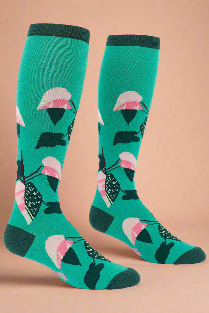 Green socks with pink and black floral pattern on a white background