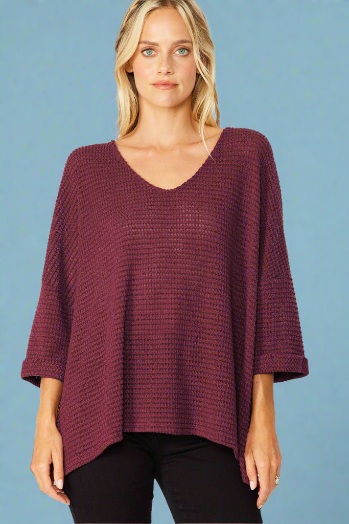 Model is wearing an oversized waffle knit top in the color cinnamon. Top features a soft v neck and cuffed sleeves. 