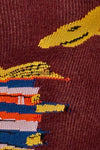 Close-up of a sock with colorful pattern on a maroon background