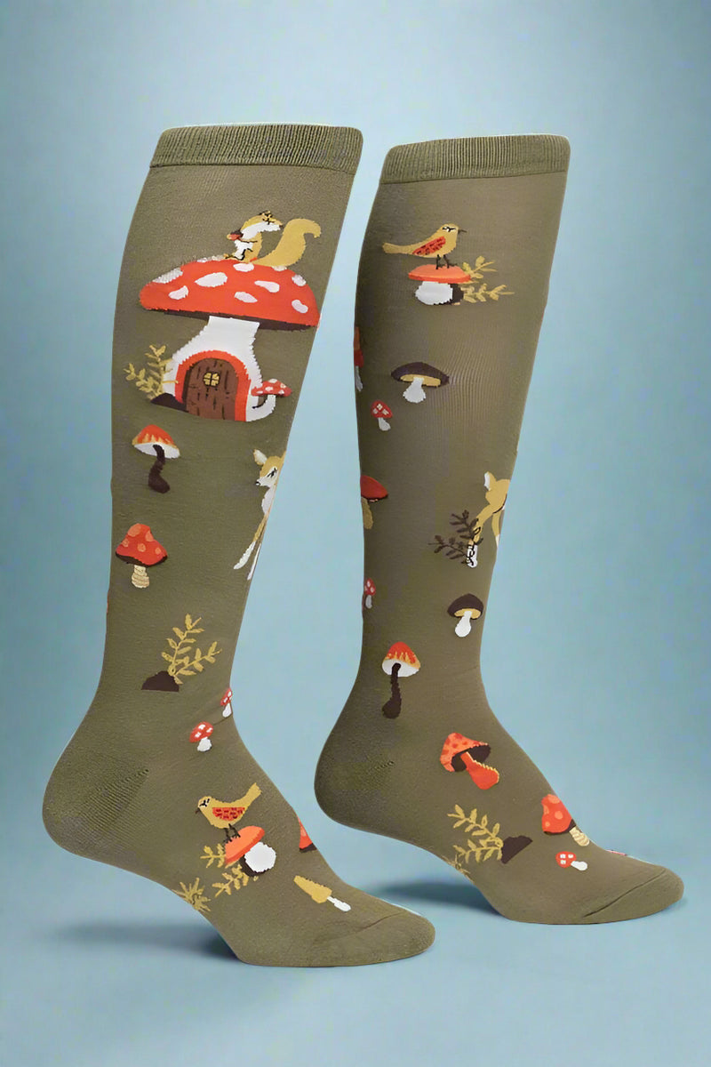 Pair of green knee-high socks with mushroom and bird design on a light gray background