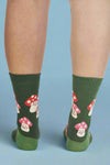 Green socks with mushroom pattern worn by a person on a white background