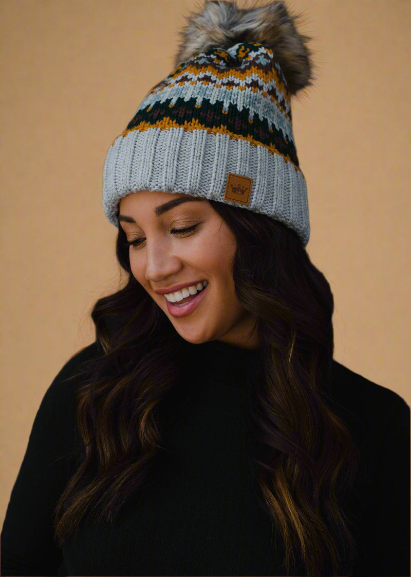 Woman wearing a patterned knit beanie with a pom-pom on a black background