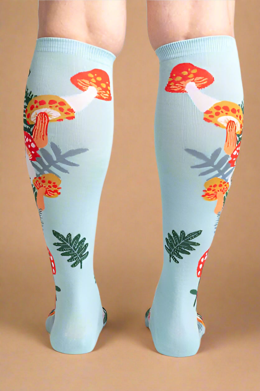 Light blue knee-high socks with mushroom pattern worn by a person on a light gray background