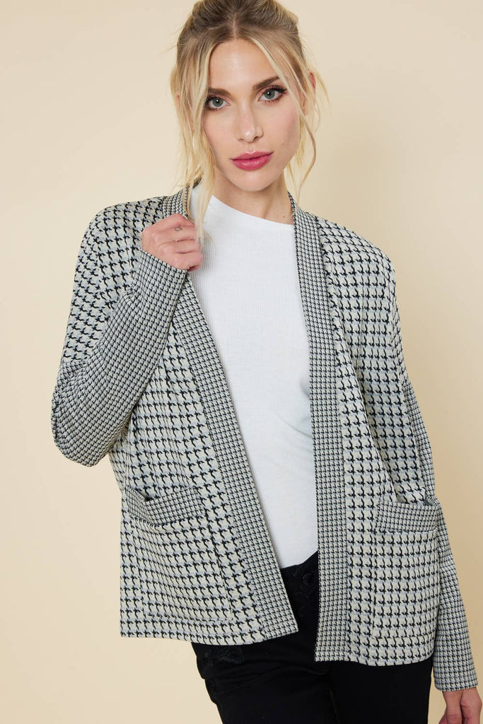 Model is wearing an open cardigan with houndstooth patterns and open pockets. 