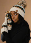 Person wearing a patterned knit hat and mittens against a black background