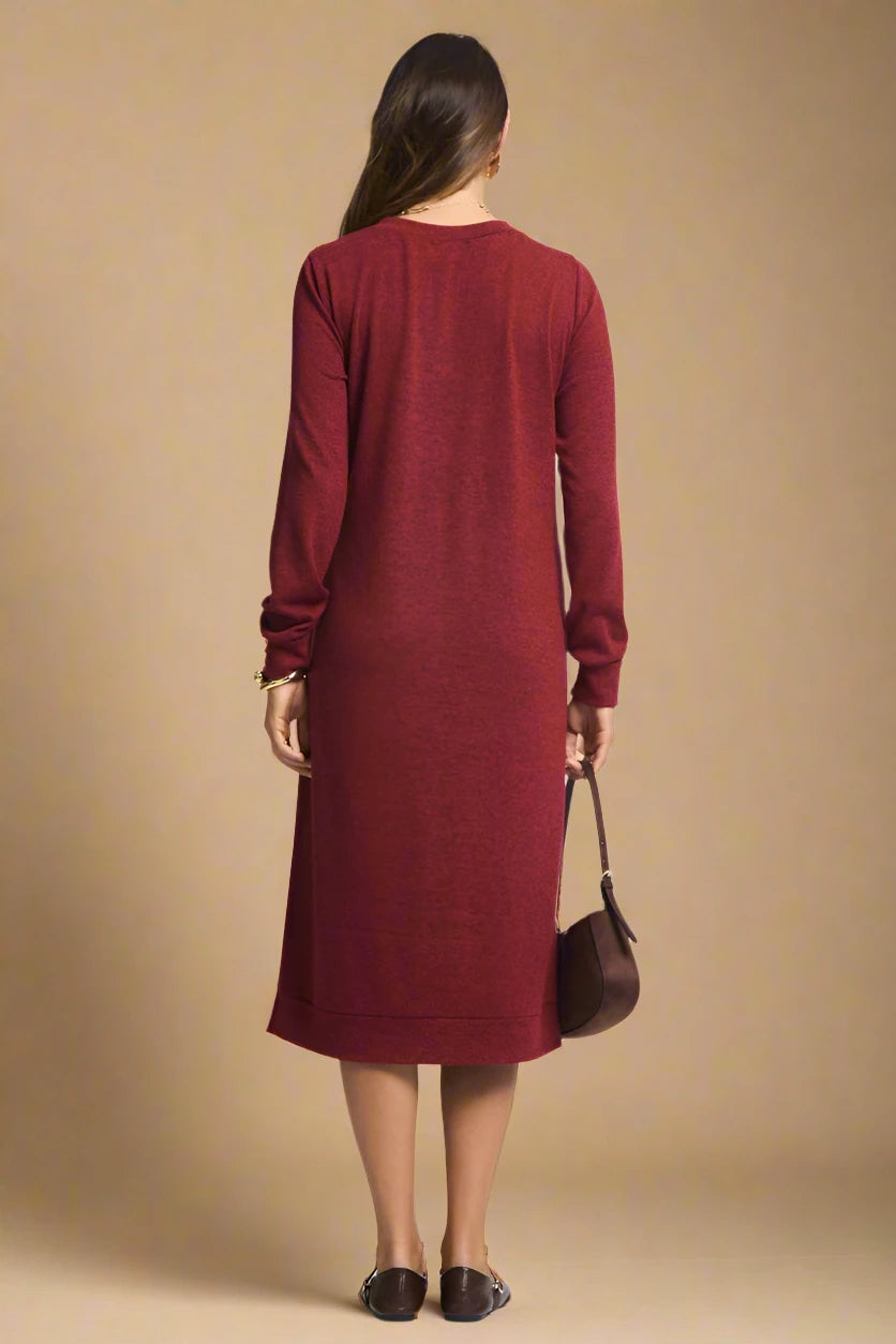 Woman wearing a burgundy dress holding a brown bag on a plain background