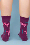 Purple socks with pink dragon design worn by a person on a white background