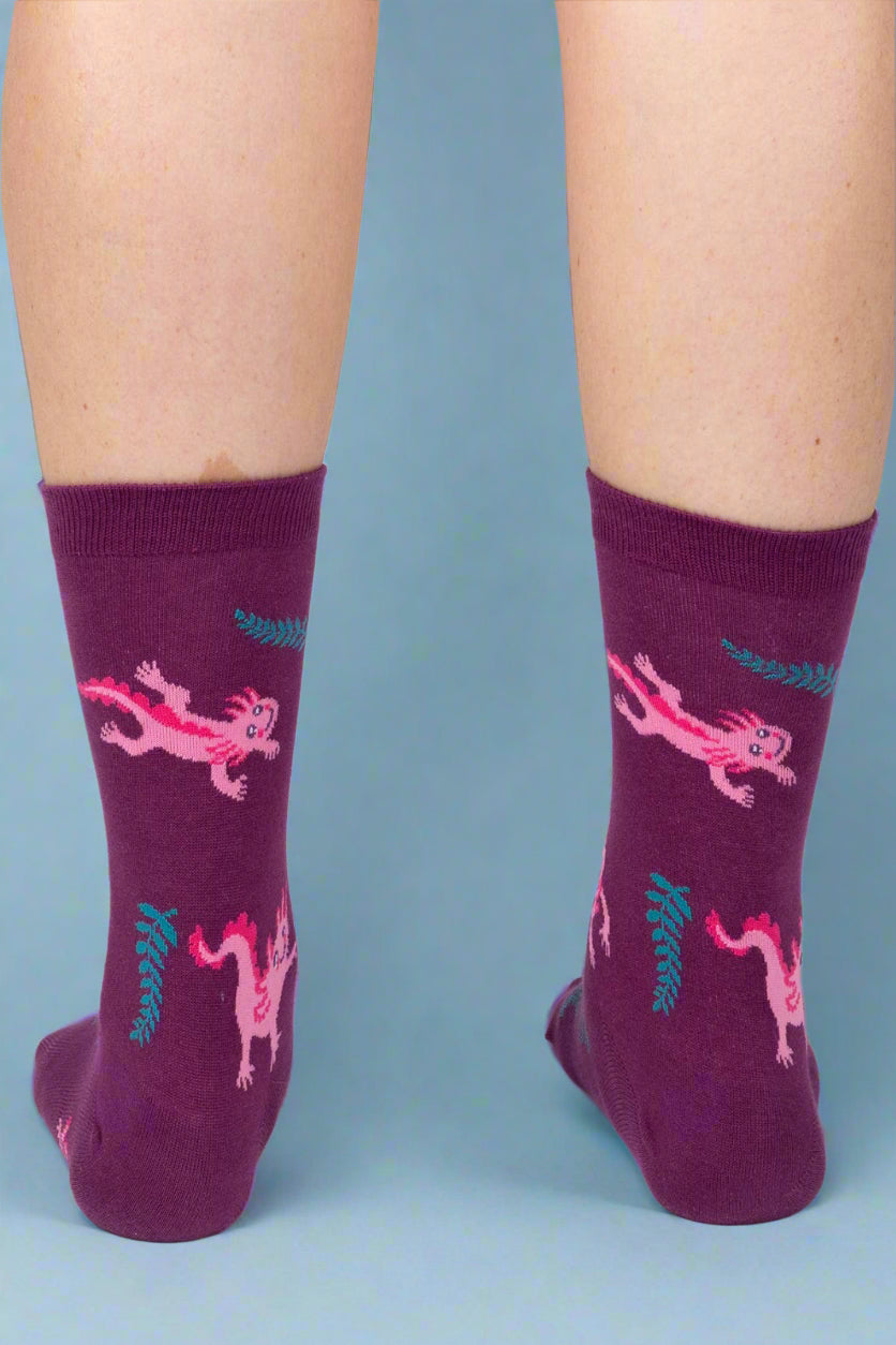 Purple socks with pink dragon design worn by a person on a white background