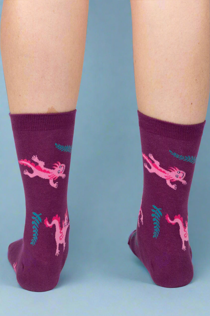 Purple socks with pink dragon design worn by a person on a white background