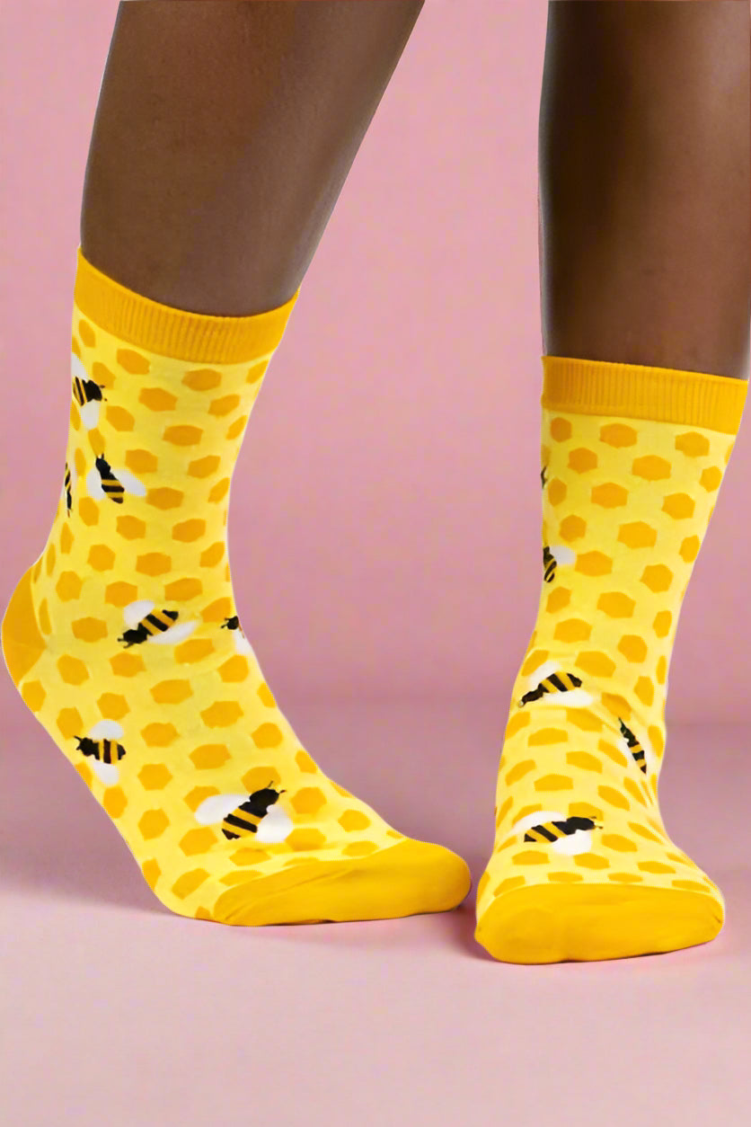 Yellow socks with black patterns worn by a person on a white background
