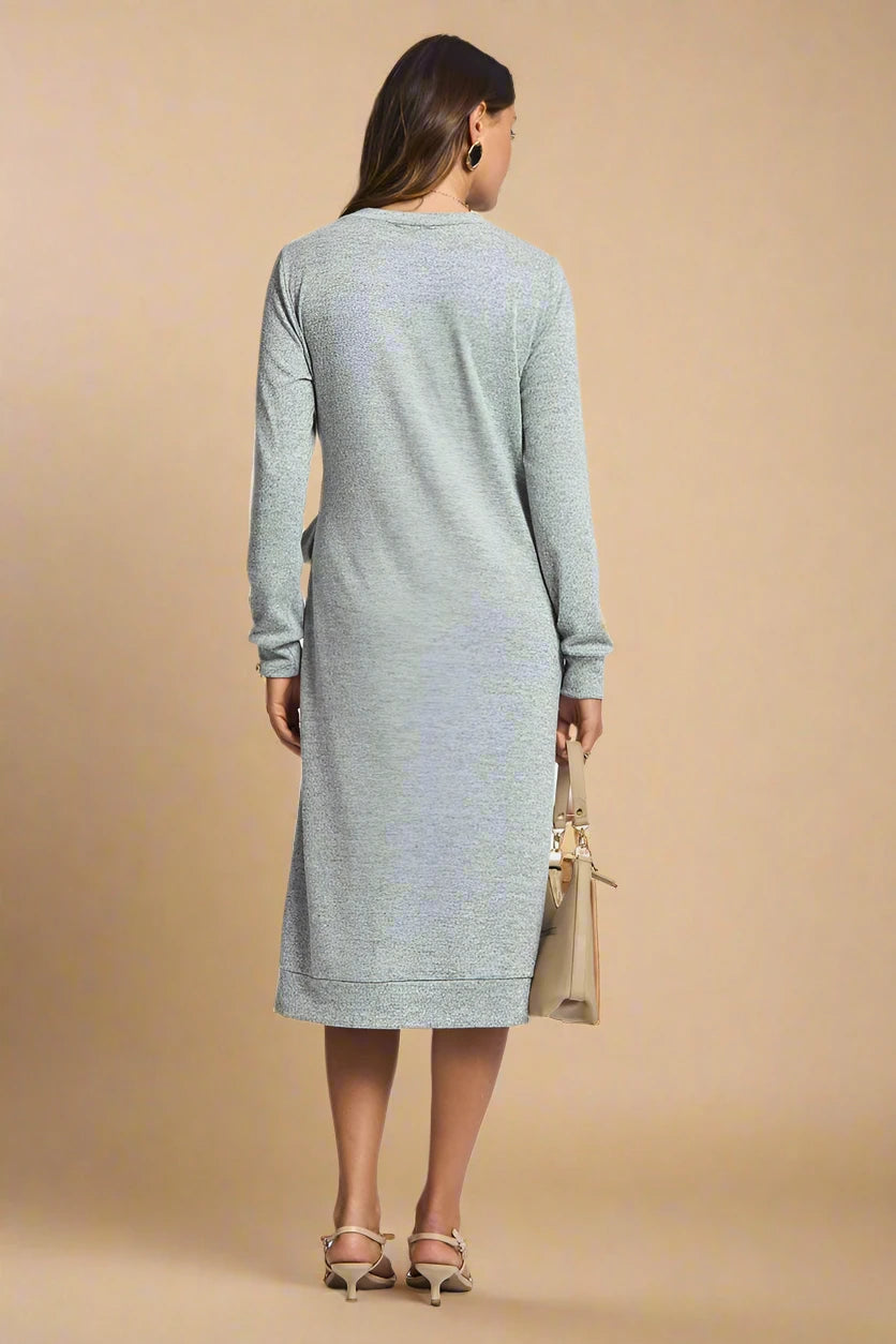 Woman wearing a gray dress holding a beige bag on a plain background