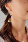 Model wears a gold stainless steel hoop earring featuring a navy blue, enamel half-moon and openwork stainless steel bell pendant.