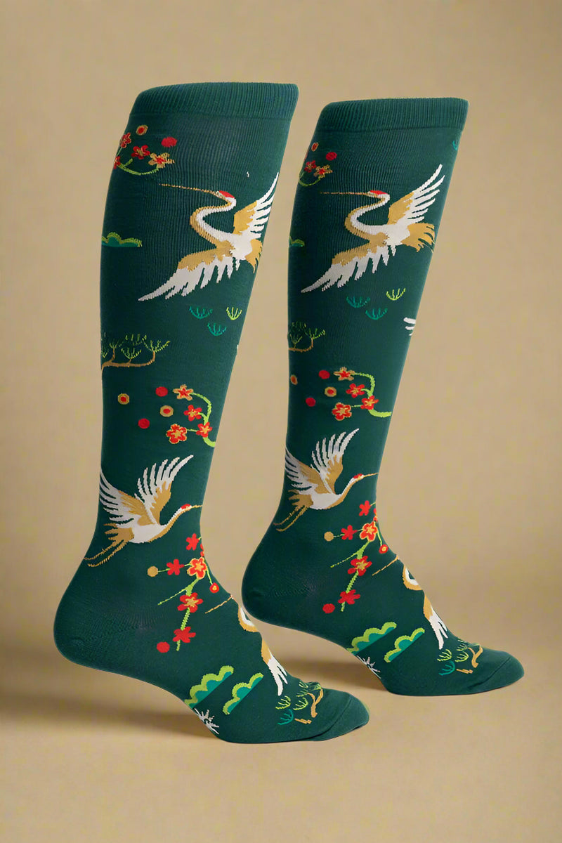 Green knee-high socks with crane and floral patterns on a white background