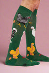Green knee-high socks with chicken designs worn by a person on a white background