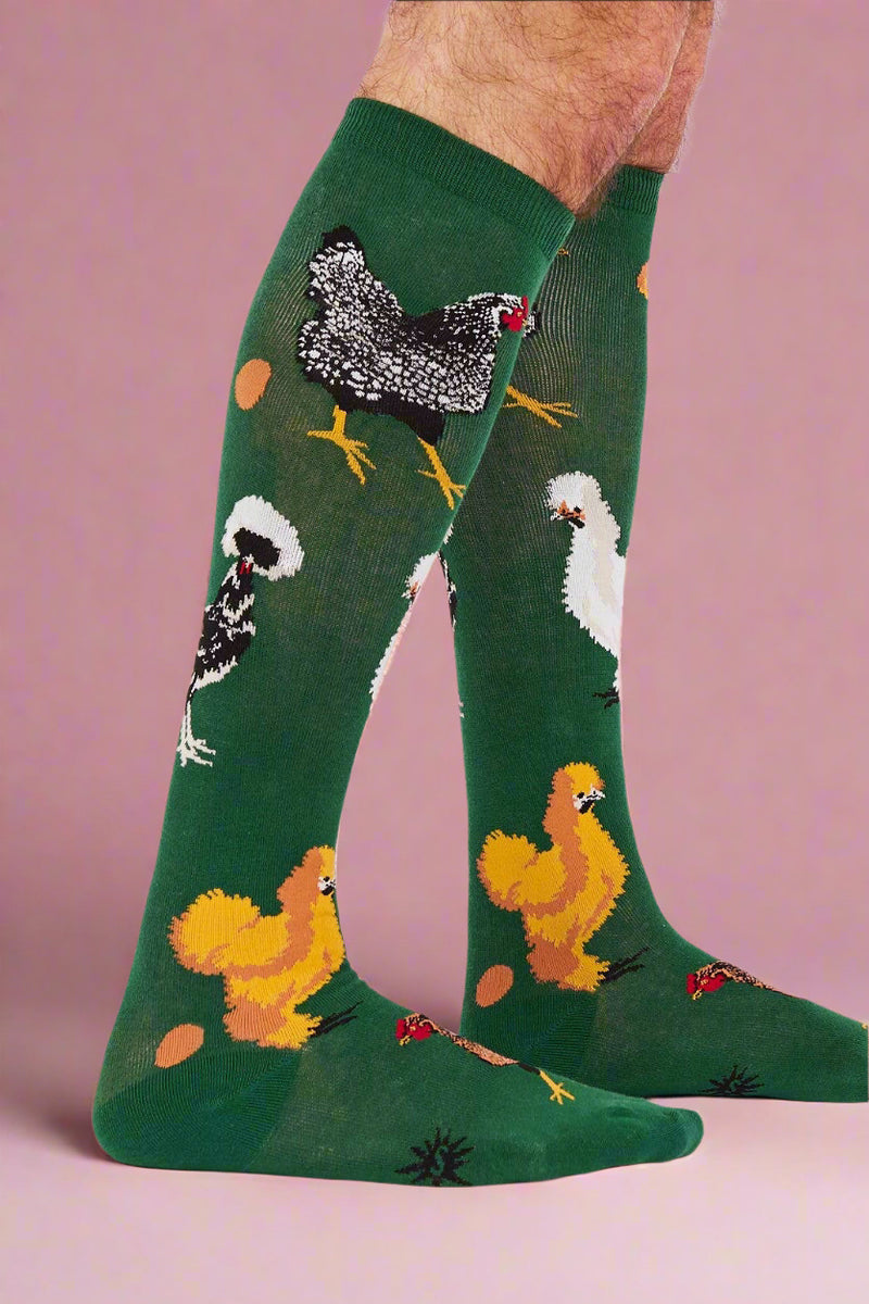 Green knee-high socks with chicken designs worn by a person on a white background