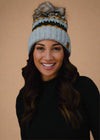 Woman wearing a colorful knit beanie against a black background
