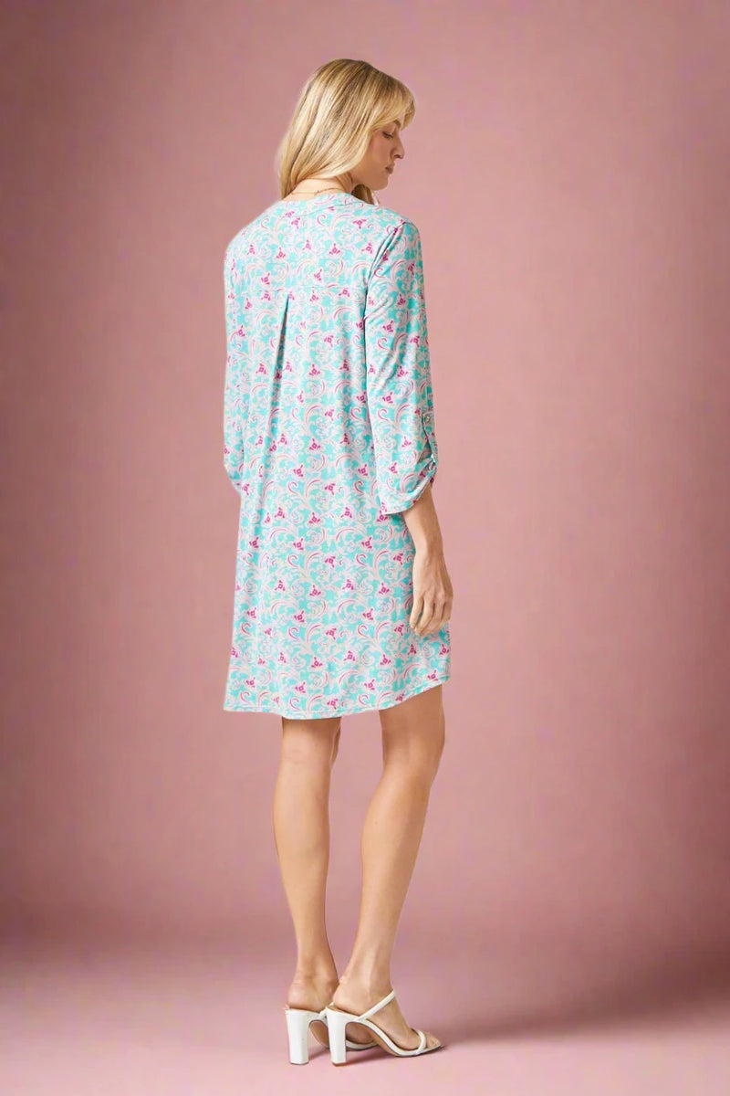 Woman wearing a light blue dress with pink pattern on a plain background