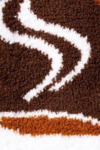 Close-up of a brown and white patterned rug with a snake design.