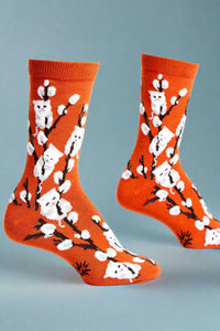 Orange socks with white floral and kitten patterns on a white background