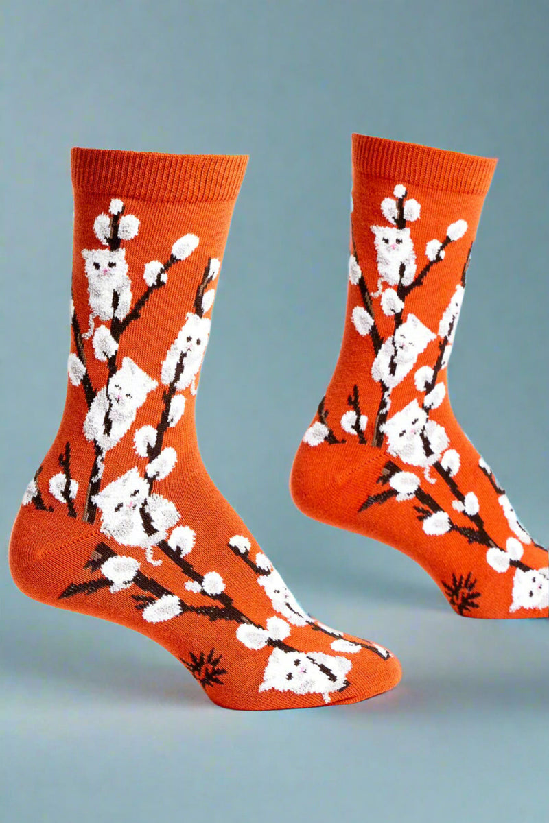 Orange socks with white floral and kitten patterns on a white background