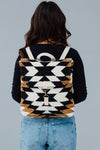 A black, white and brown Aztec pattern backback. With adjustable straps, clasp closures, and a handle loop. 