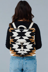 A black, white and brown Aztec pattern backback. With adjustable straps, clasp closures, and a handle loop. 