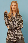 A long sleeve button up collared top in a black and white floral pattern.