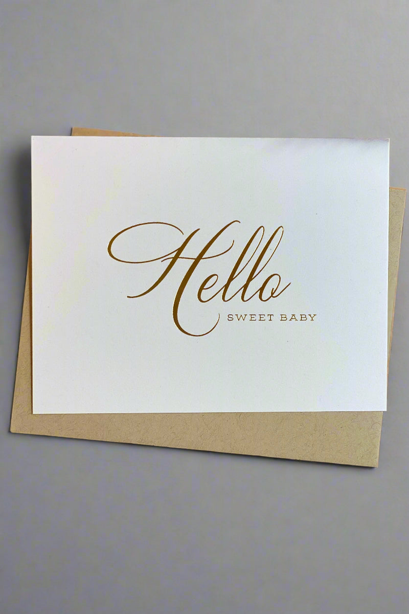 White greeting card with calligraphy that reads ‘Hello Sweet Baby’ and gold envelope.
