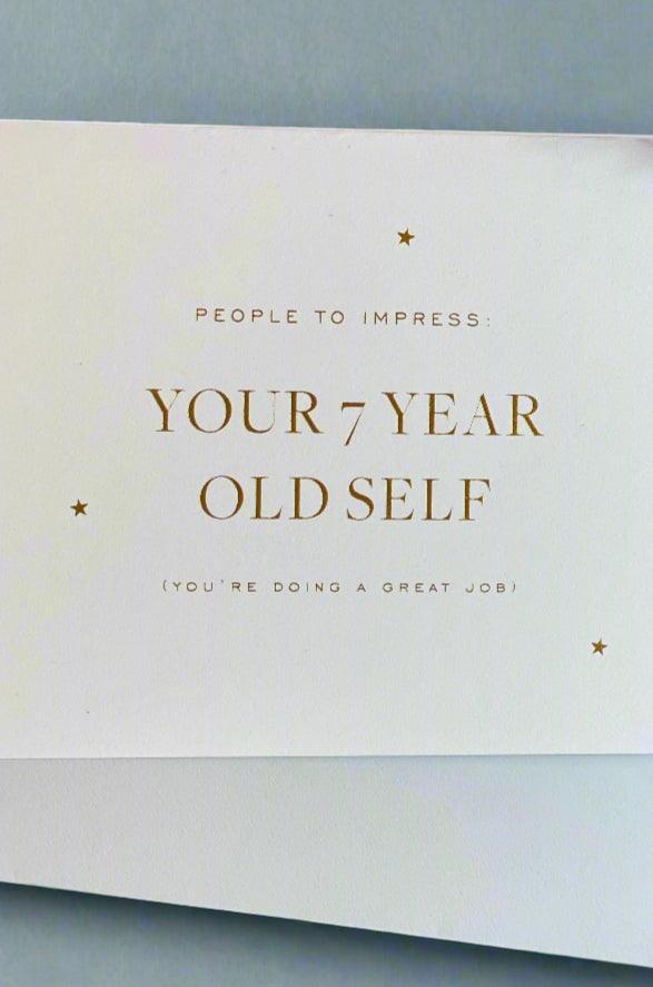 A minimalist greeting card in white with gold text that reads ‘People To Impress: Your 7 Year Old Self (You’re Doing A Great Job)’