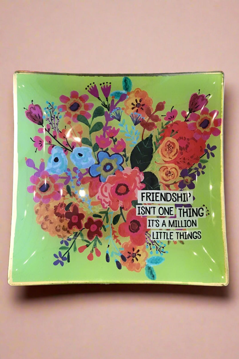 Little glass catch-all plate with green background and bright floral design that reads ‘Friendship isn’t one thing, it’s a million little things.’