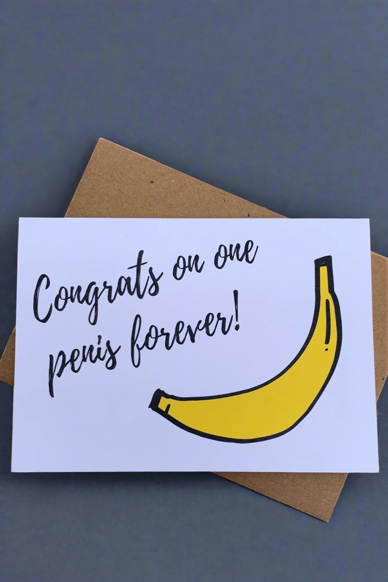 A white greeting card with the image of a banana and black text that reads ‘Congrats on one penis forever!’