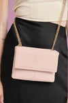 Gold flap style crossbody with dainty gold stud detailing around the perimeter of the front panels. Gold chain for strap with a pink shoulder pad for comfort. 