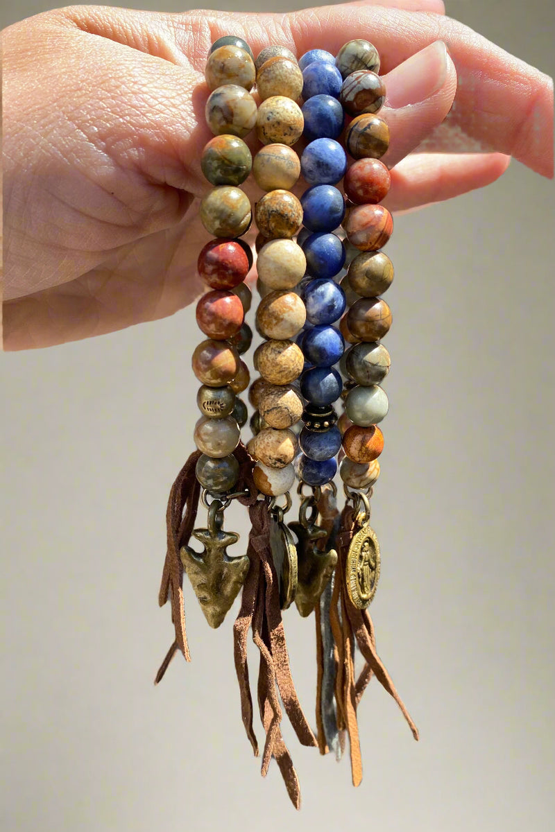 Assortment of stone bead bracelets with brass charms and leather tassels.