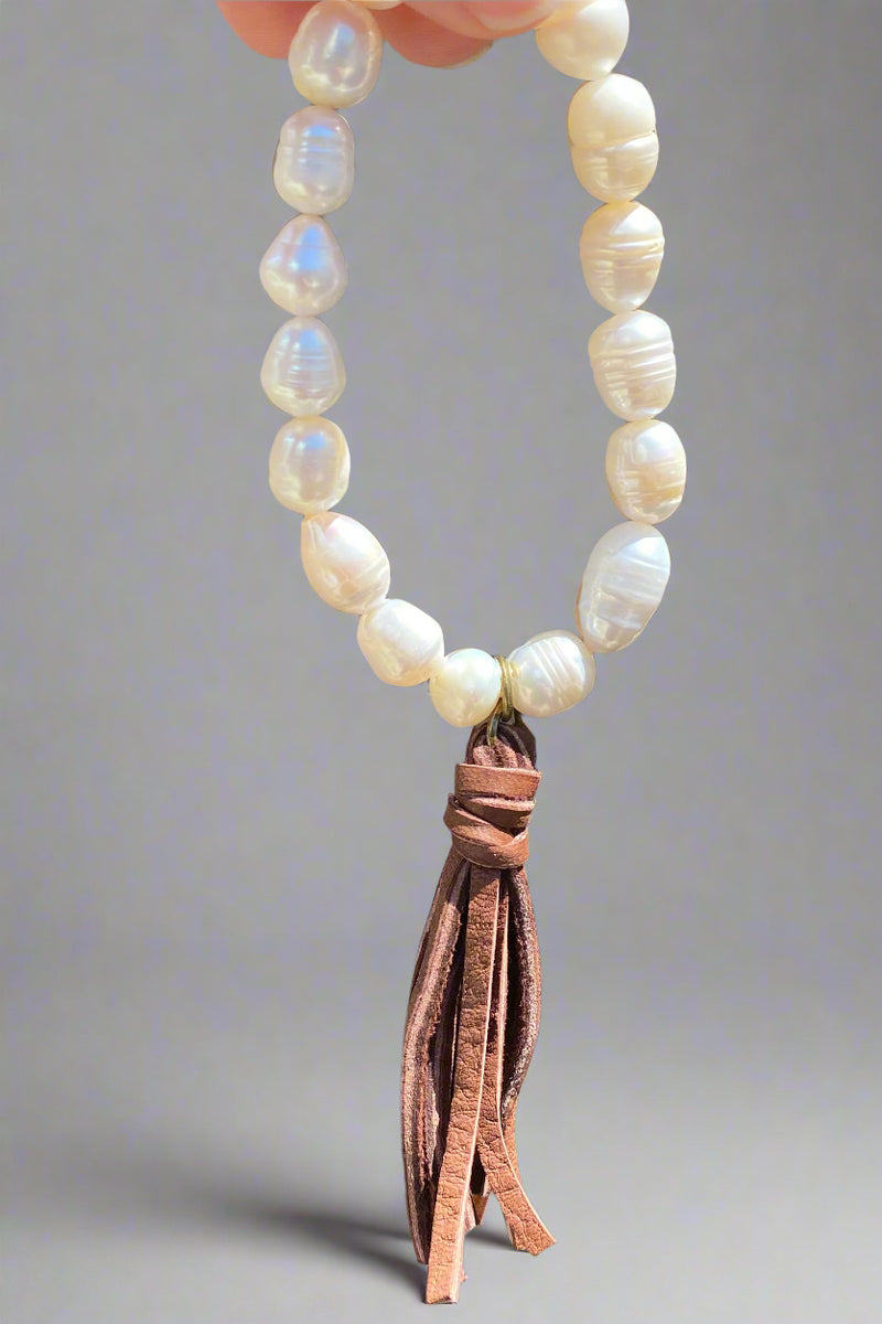 This gorgeous bracelet is made with stretchy elastic and features delicate pearl beads and a genuine leather tassel.