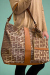 A large shoulder bag with a brown pattern features a zip closure and inside pockets. Includes an extra wristlet bag.