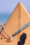 Grey and Teal braided bracelet with adjustable pulls and a small silver 4ocean charm. 