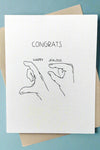 A simple white greeting card with the image of a hand measuring a lot with the word ‘happy’ above it and a hand measuring a little with the word ‘jealous’ above it and the word ‘CONGRATS’ written above it all.