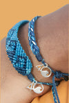 Shades of blue woven bracelet with wave pattern and adjustable slider and small silver 4ocean charm. 