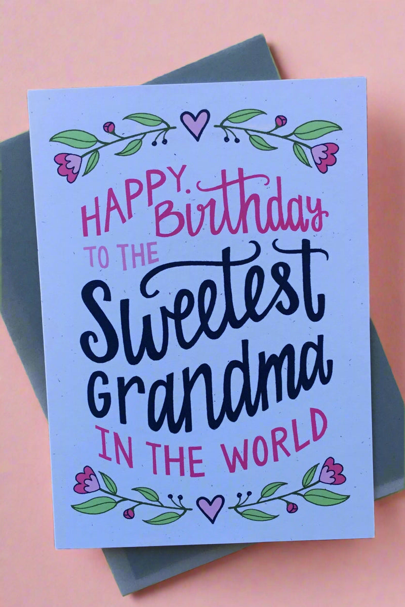 A greeting card with floral boarder on top and bottom and text that reads ‘Happy Birthday to the Sweetest Grandma in the World’.
