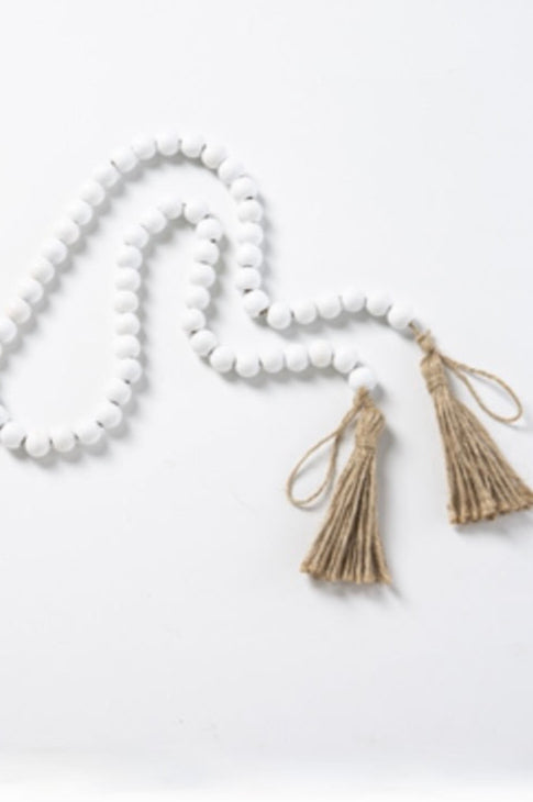 A strand of white wood bead garland with tan tassels at each end.