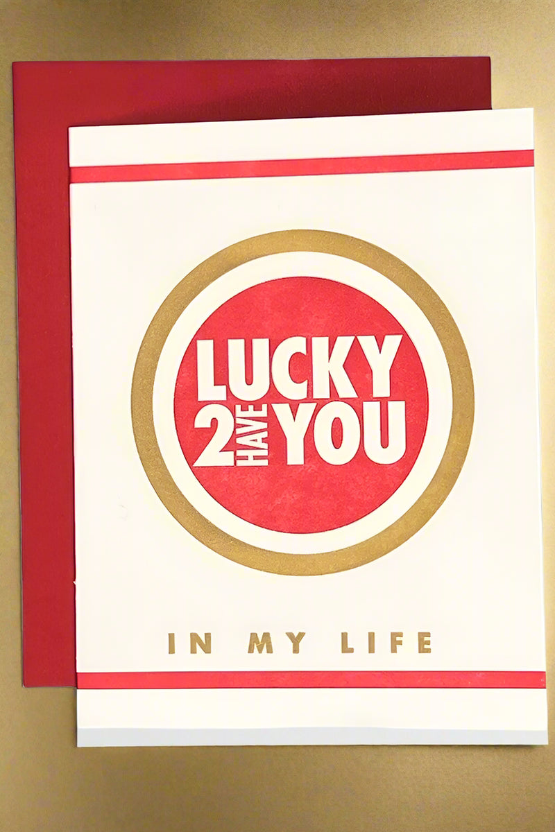 A red, white, and gold card that says “lucky 2 have you in my life.”