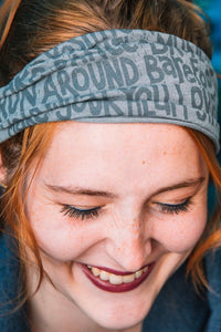 Soft light grey headband with a "manifesto" printed on it in a contrasting grey. 