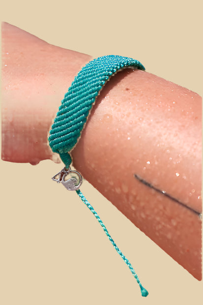Teal woven bracelet with adjustable slider and small silver 4ocean charm. 