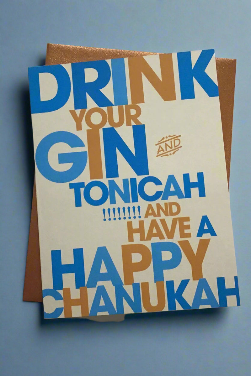 A cream card with the words “ Drink your gin and tonicah!!!!!!!! and have a Happy Chanukah” in blue and gold letters.