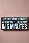 A black rectangle sign that says “I don’t even believe myself when I say I’ll be ready in 5 minutes” in white.